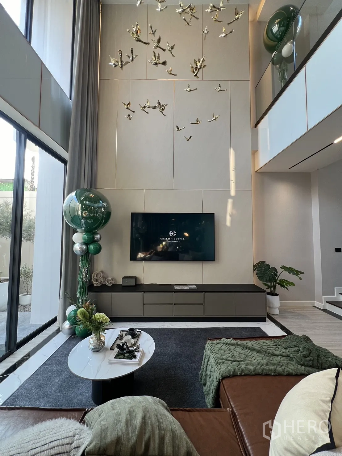 Detached House for sale in Lat Phrao, Bangkok - Double-height living room with TV wall, bird art installation and large windows.