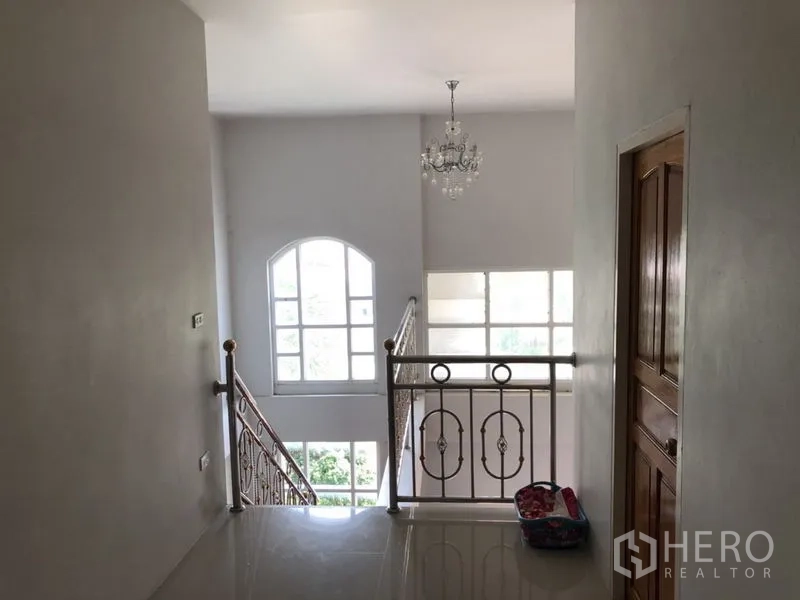 Detached House for sale in Lam Luk Ka, Pathum Thani - Upper landing with chandelier and tall arched windows.