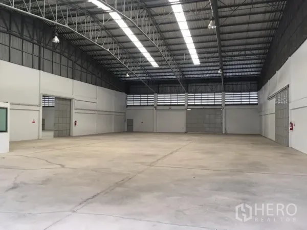 Warehouse for rent in Si Racha, Chon Buri - Open warehouse floor with polished concrete, multiple roller shutters and bright linear lighting.