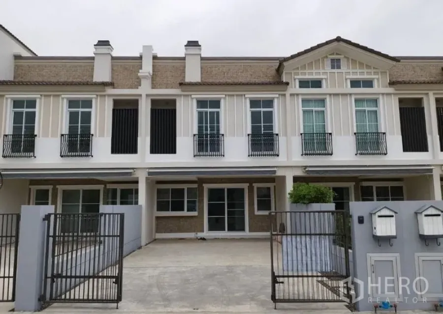 Townhouse for rent in Prawet, Bangkok - Front elevation of the townhouse with twin metal gates and driveway parking.