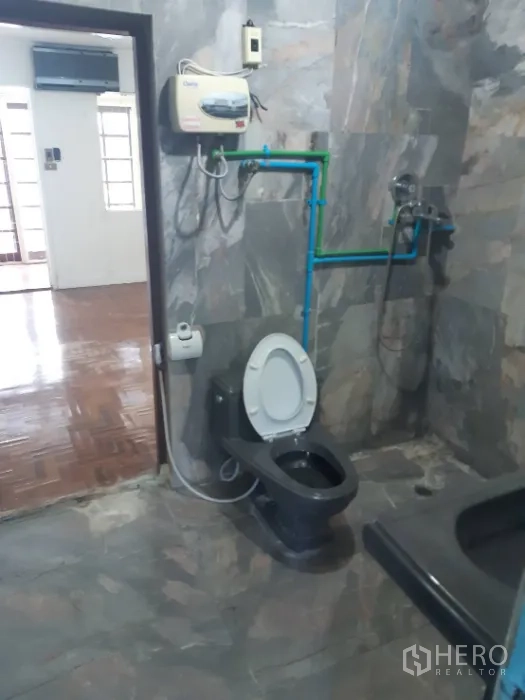 Townhouse for rent in Khlong Toei, Bangkok - Bathroom with stone‑look tiles, black fixtures, shower and exposed piping.