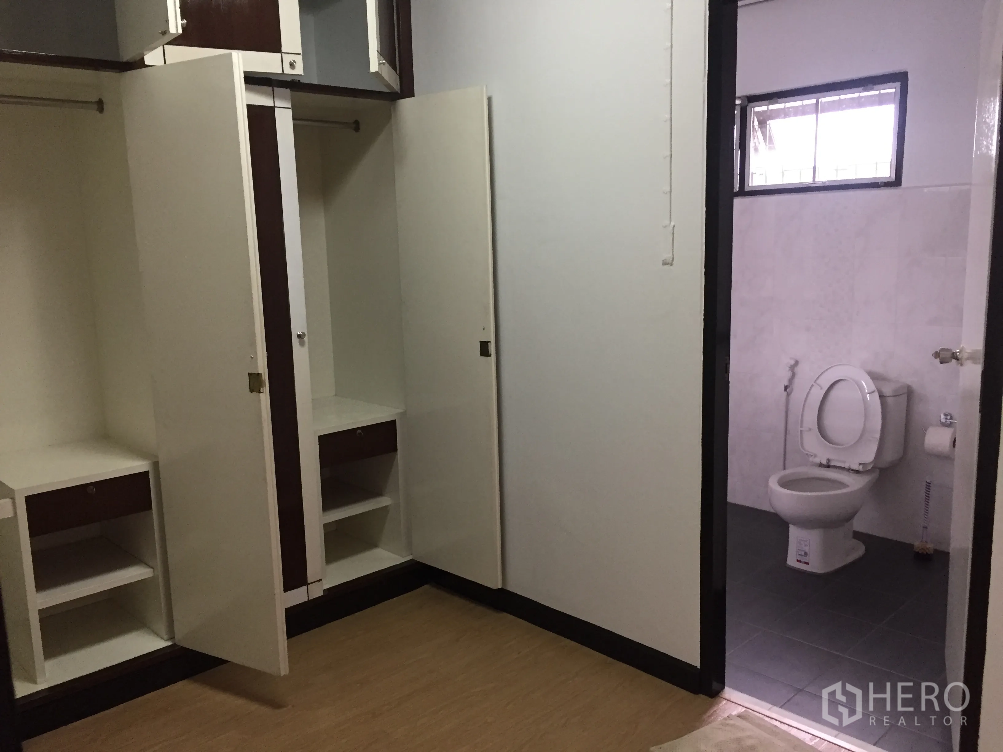 联排别墅 出租在Khlong Toei, Bangkok - 卧室内置衣柜敞开，门通向瓷砖卫浴。