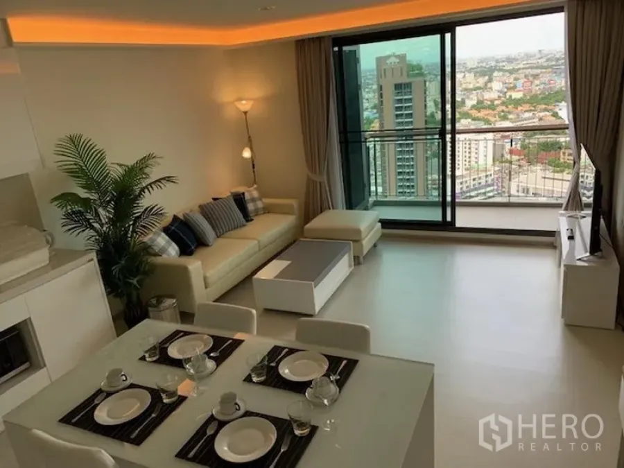 Condominium for rent in Khlong Toei, Bangkok - Open-plan living room with sofa, dining set and balcony overlooking Bangkok skyline in an Ekkamai condo