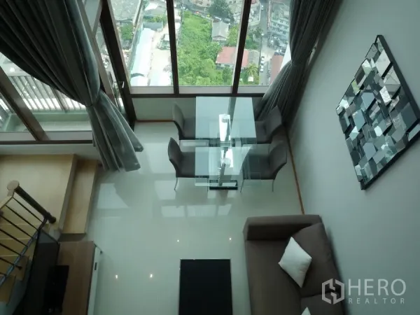 Condominium for rent in Khlong Toei, Bangkok - Top-down view of glass dining table by tall windows and balcony in the duplex condo.