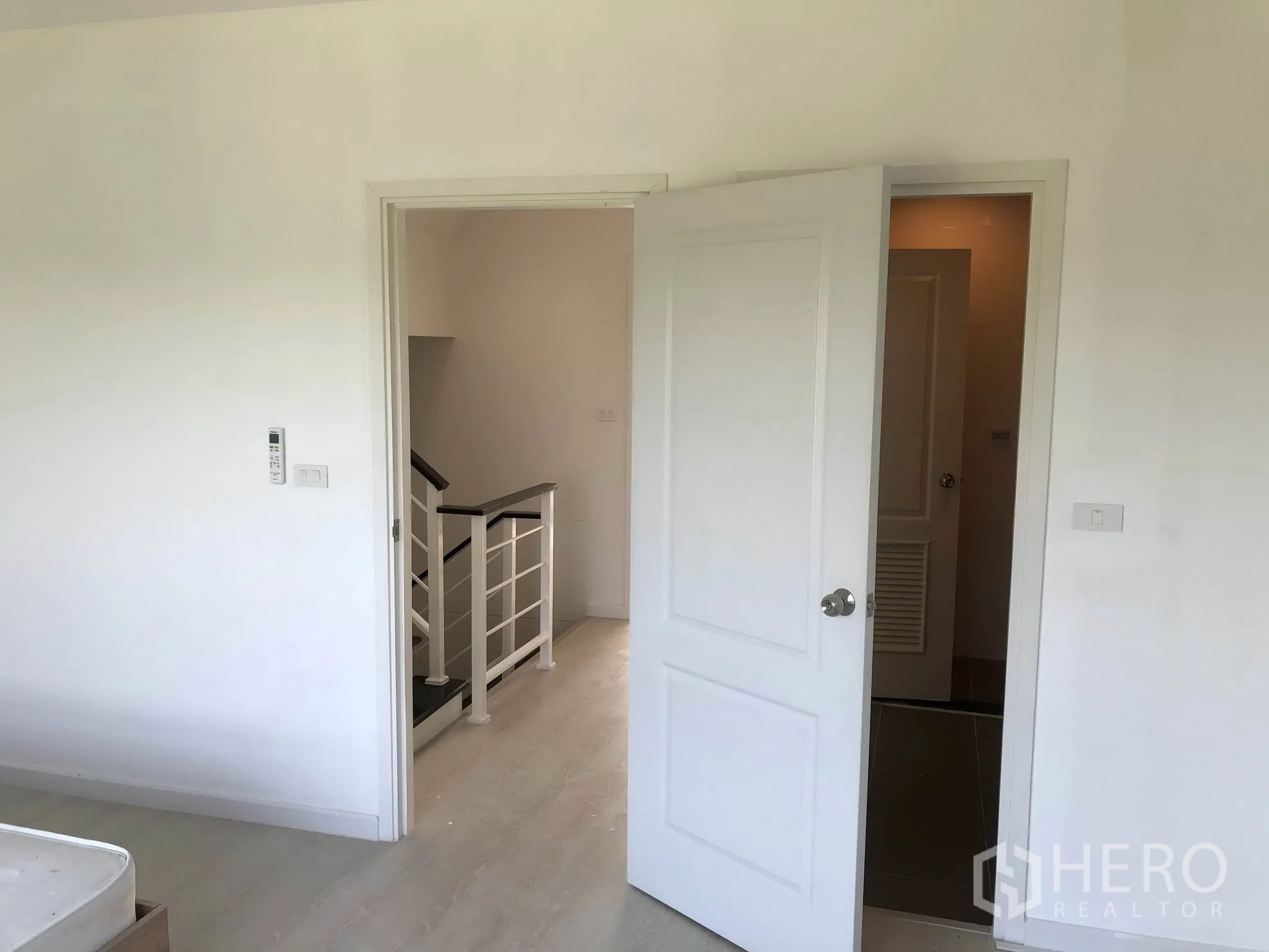 Townhouse for rent in Bang Kapi, Bangkok - Upper-floor landing with white doors to bedroom and bathroom beside a modern stair rail.