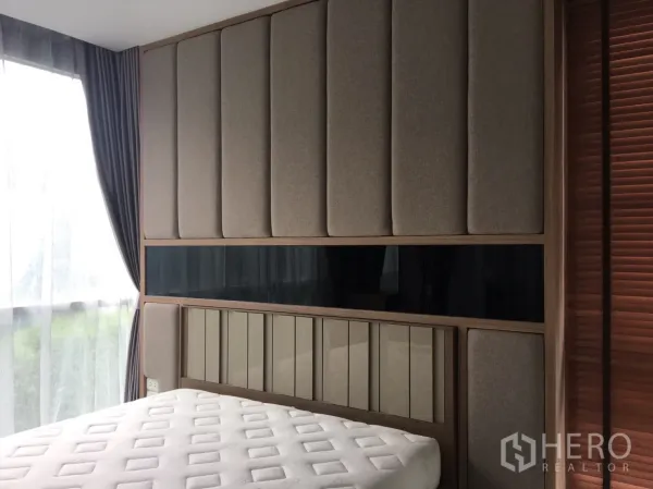 Condominium for sale in Phra Khanong, Bangkok - Sunlit bedroom with a large padded headboard, full-height windows and blackout curtains.