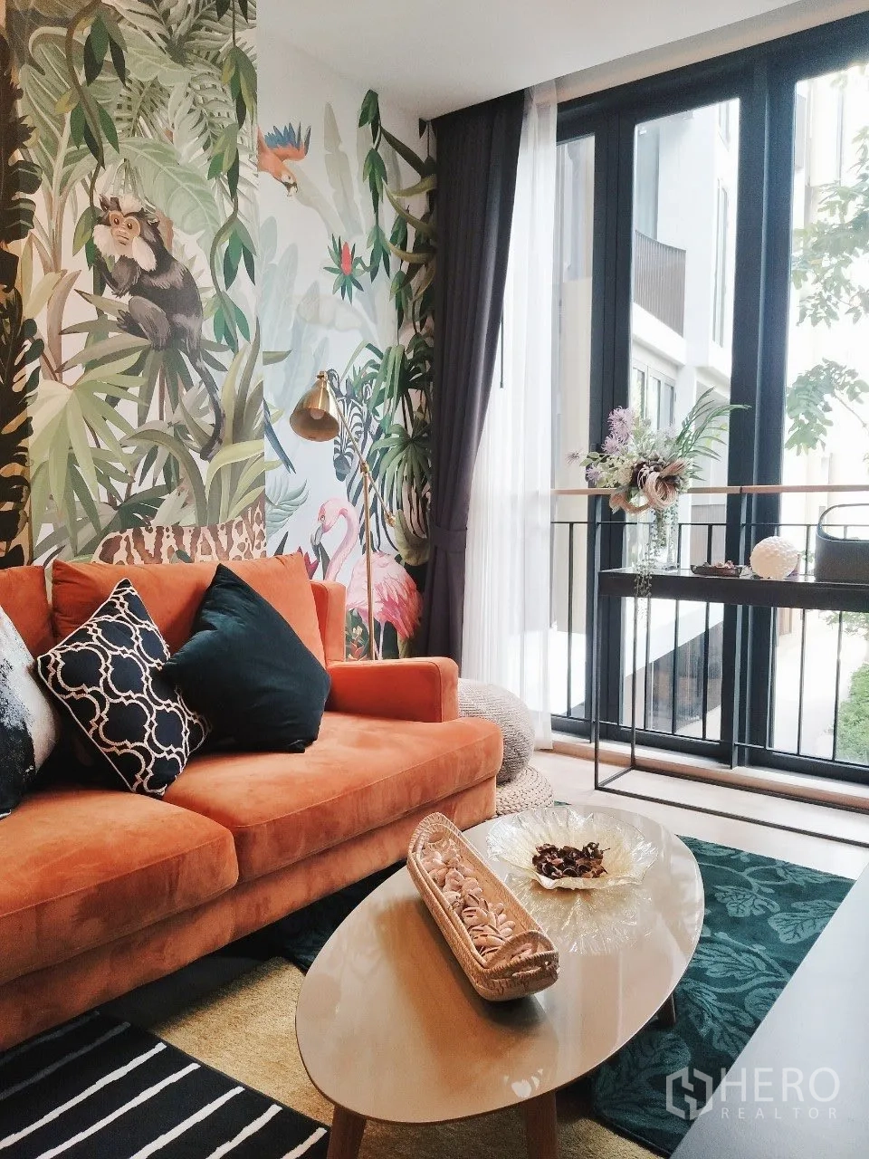 คอนโด for rent in Watthana, Bangkok - ห้องนั่งเล่นโซฟาสีส้ม ผนังลายทรอปิคัล โต๊ะกลาง และหน้าต่างสูง