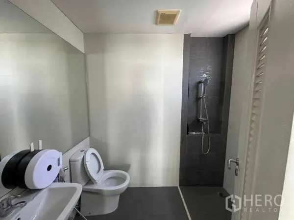 Home Office for rent in Chatuchak, Bangkok - Modern bathroom featuring a walk-in shower, large mirror, toilet, and sink.