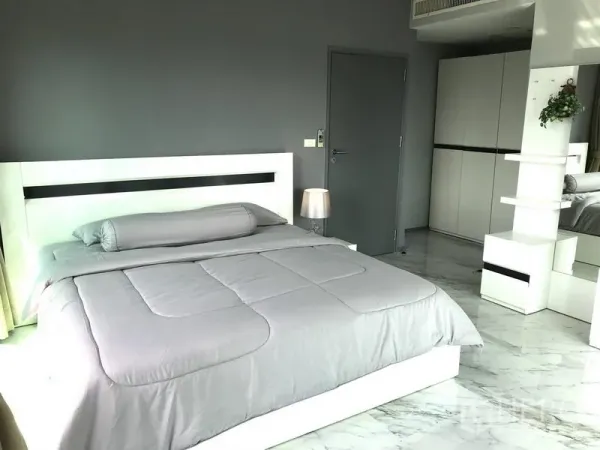 Condominium for rent in Khlong Toei, Bangkok - Spacious bedroom with grey walls, white bed frame and built-in wardrobe.