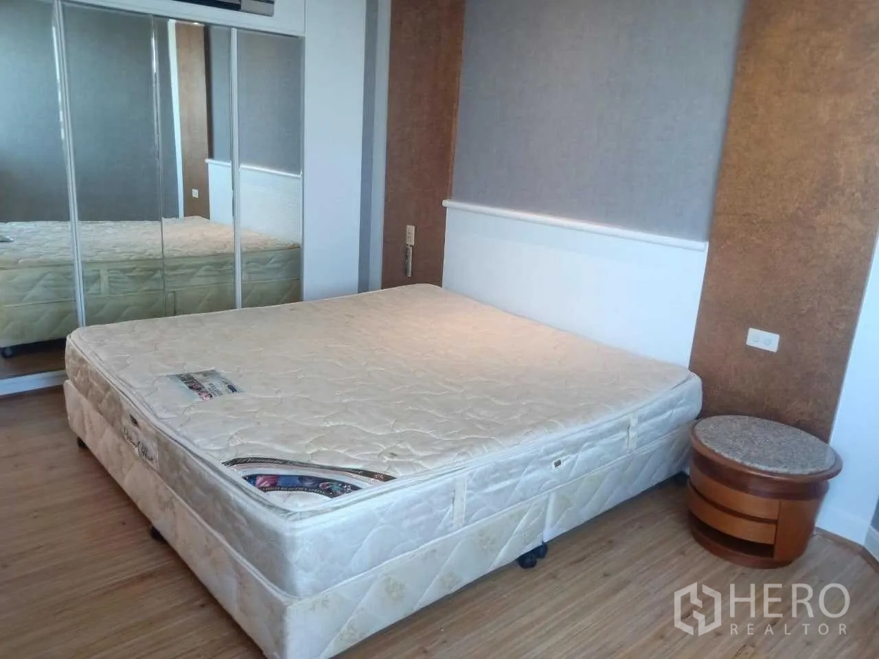 Condominium for rent in Khlong Toei, Bangkok - Bedroom with mirrored wardrobe, bedside table and wood floors.
