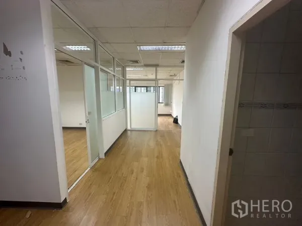 Office Space for rent in Watthana, Bangkok - Glass-partitioned office corridor with wood-look flooring and ceiling lights.