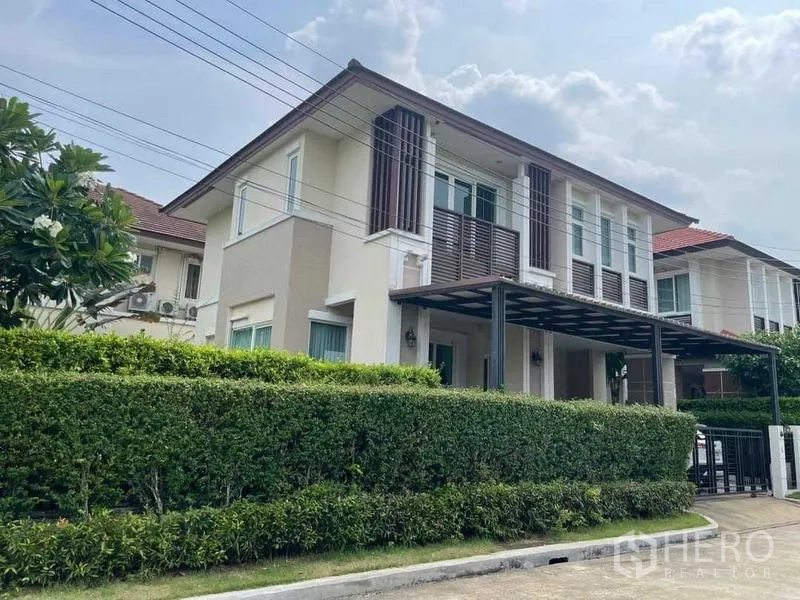 Detached House for sale in Bang Kruai, Nonthaburi - Contemporary façade from another angle showing hedge fence and covered parking.
