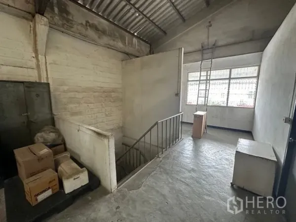 Factory for rent in Lam Luk Ka, Pathum Thani - Upper landing with concrete floor, metal stairs, and window inside the factory.