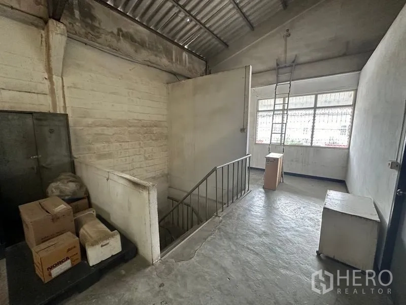 Factory for rent in Lam Luk Ka, Pathum Thani - Upper landing with concrete floor, metal stairs, and window inside the factory.