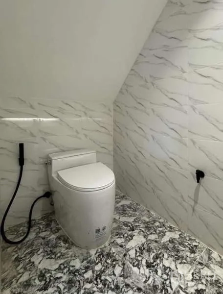 Townhouse for rent or sale in Prawet, Bangkok - Compact under-stair powder room with marble-look tiles.