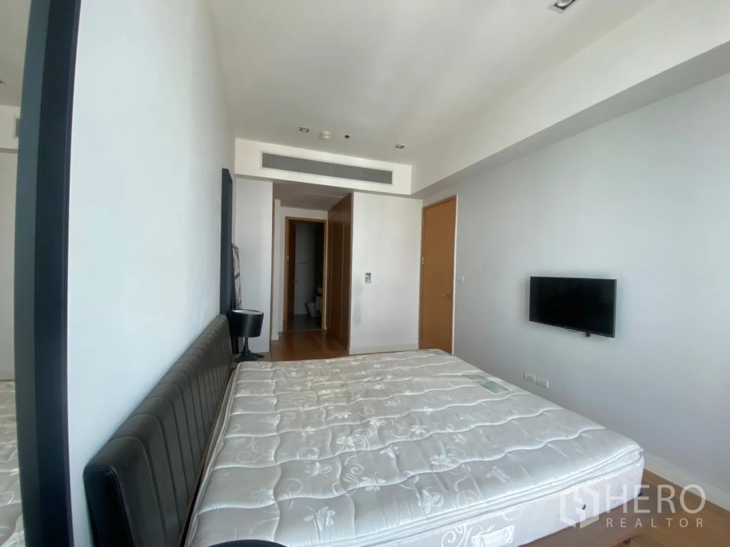 Condominium for rent or sale in Khlong Toei, Bangkok - Master bedroom alternate angle showing padded headboard, corridor wardrobes and ensuite access.