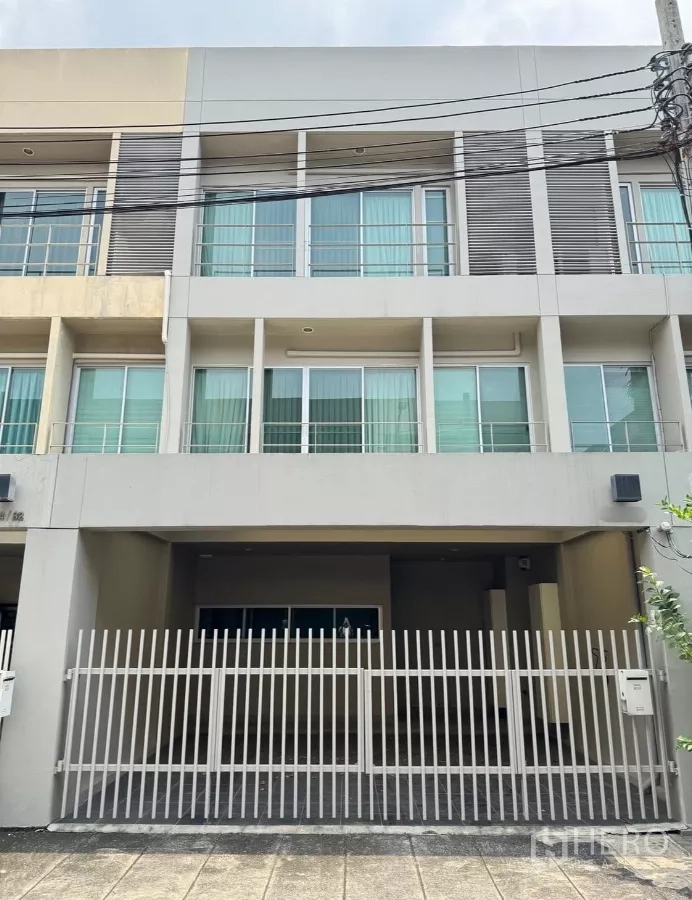 Townhouse for rent in Suan Luang, Bangkok - Modern three-storey townhouse facade with gated two-car carport at Noble Cube.