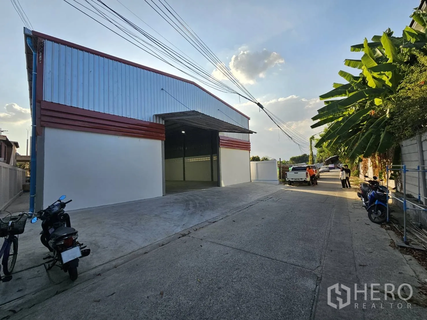 Warehouse for rent in Mueang Samut Prakan, Samut Prakan - Street view of the warehouse exterior with open driveway and parked vehicles.