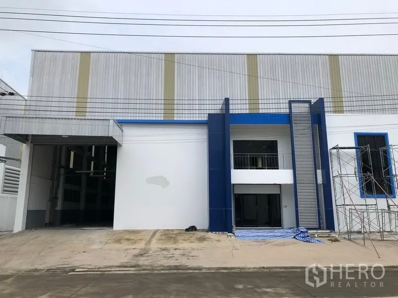 Factory for rent or sale in Samut Prakan - Modern factory facade in Bang Phli with blue accents, office entrance and a wide loading bay.