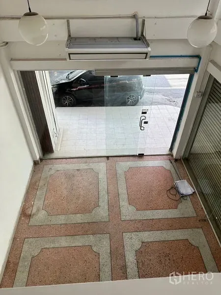 Shophouse for rent in Bangkok - Ground-floor retail area with glass storefront and terrazzo flooring seen from mezzanine.