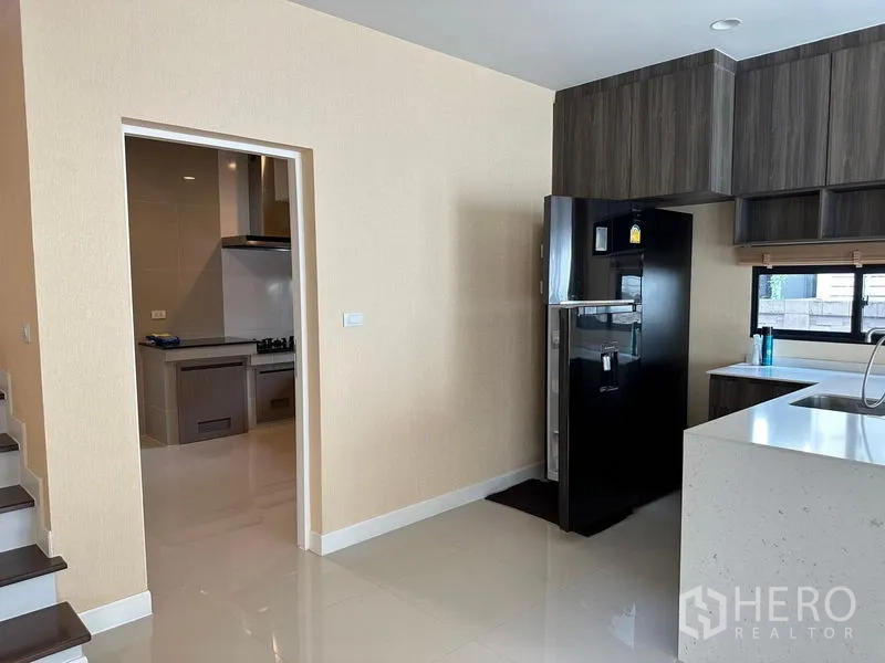 Detached House for rent or sale in Lam Luk Ka, Pathum Thani - Pantry with island counter and overhead cabinets next to doorway to the Thai kitchen and stairs.