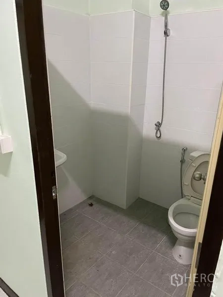 Shophouse for rent in Phaya Thai, Bangkok - Compact bathroom with wall-mounted shower, white tiles and gray floor.