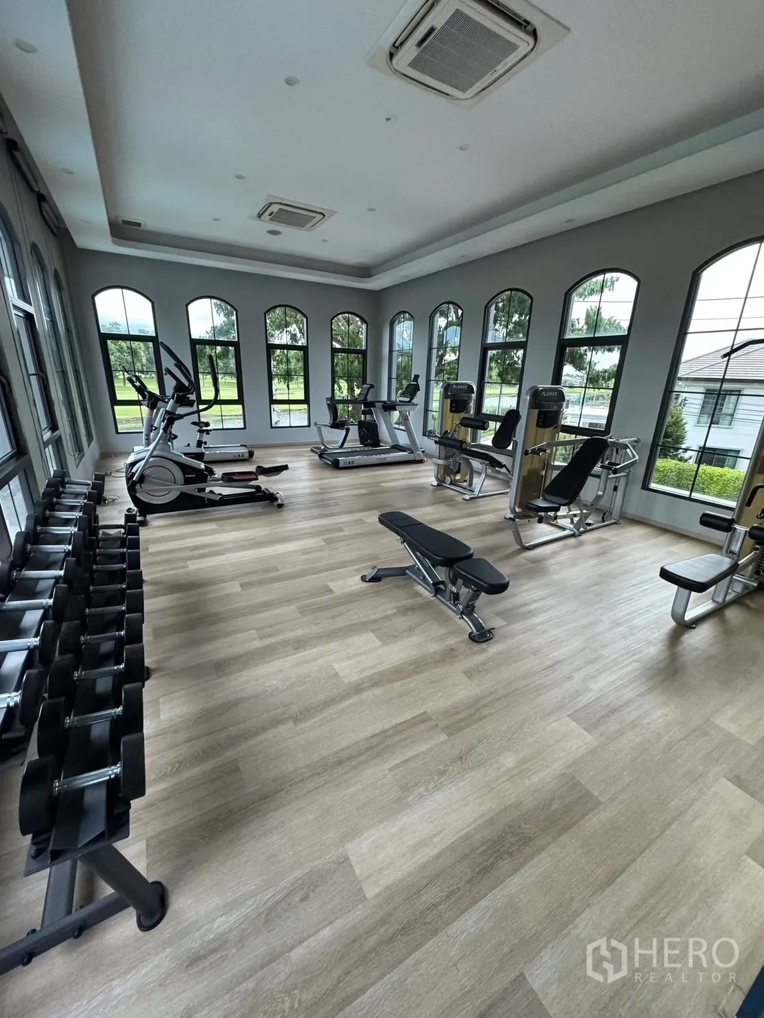 Detached House for sale in Mueang Pathum Thani, Pathum Thani - Fitness room with cardio machines, weights and arched windows.