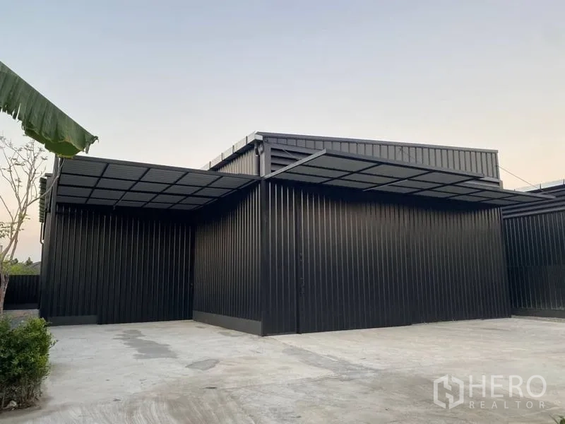 Warehouse for rent in Wang Thonglang, Bangkok - Side view of warehouse showing extended canopy, steel cladding, and generous driveway for trucks.