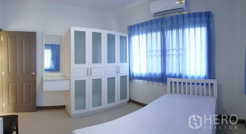 Detached House for rent in Khlong Toei, Bangkok - Secondary bedroom with blue curtains, wardrobe, air conditioner and bed.