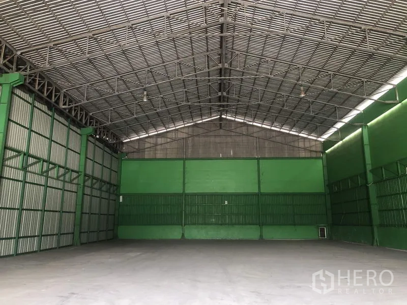 Warehouse for rent in Pak Kret, Nonthaburi - Spacious clear-span warehouse interior with a high gable roof, steel trusses and concrete floor