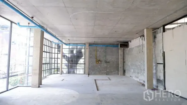 Retail Space for rent in Watthana, Bangkok - Spacious raw retail interior with concrete ceiling, visible utilities and corner glazing ideal for signage.