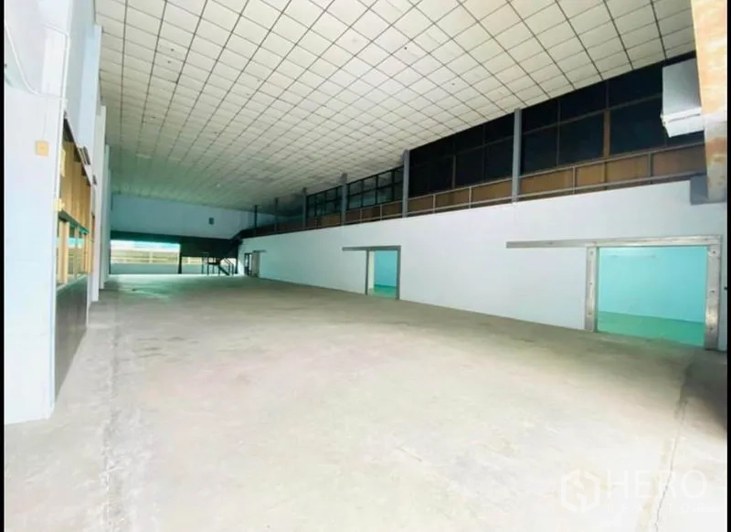 Factory for rent in Sam Phran, Nakhon Pathom - Wide storage bay with mezzanine offices and smooth concrete flooring.