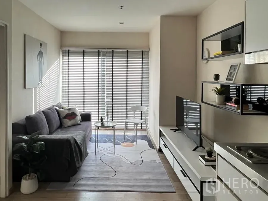 Condominium for rent in Khlong Toei, Bangkok - Long view across the living space toward the window, sofa and TV unit.