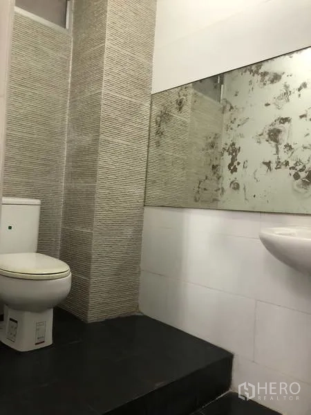 Warehouse for rent in Phra Nakhon Si Ayutthaya - Restroom with toilet, pedestal sink and a large wall mirror with textured tile feature.