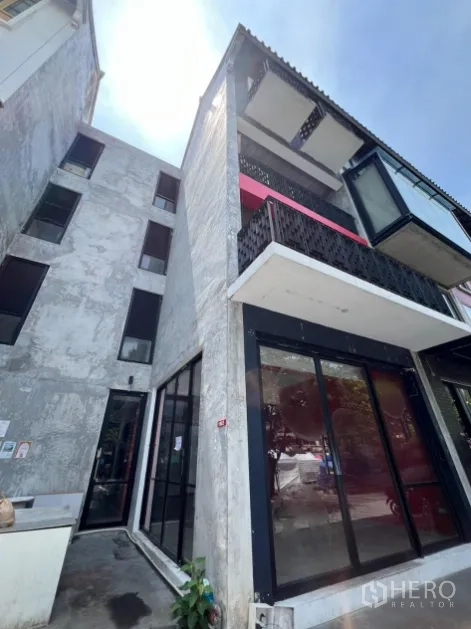 Retail Space for rent in Khlong Toei, Bangkok - Angular exterior of a four-storey building with balconies and a ground-floor shopfront.