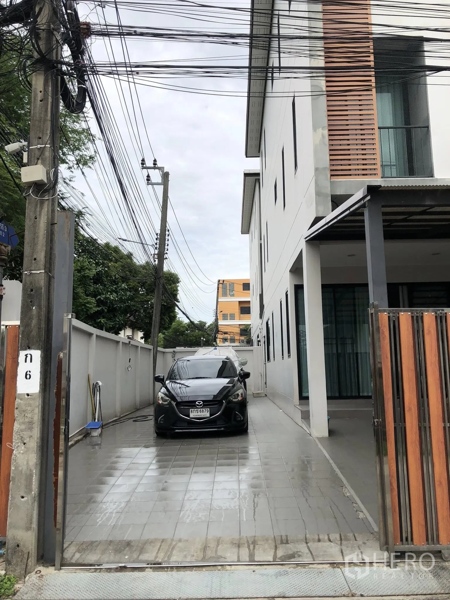Townhouse for sale in Phra Khanong, Bangkok - Long tiled driveway beside the townhouse providing multiple car parking behind a wooden gate.