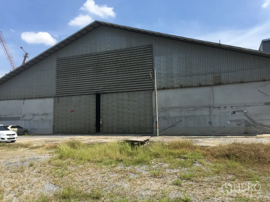 Warehouse for rent in Khlong Luang, Pathum Thani - Steel-clad warehouse exterior with wide sliding doors and a loading yard in Khlong Luang.