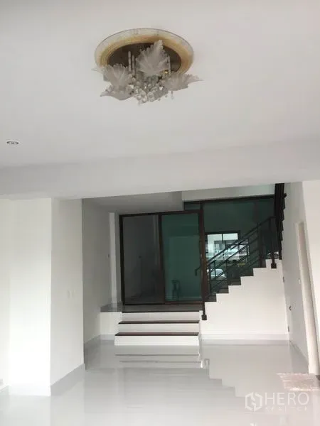 Home Office for rent in Wang Thonglang, Bangkok - Open-plan living area with chandelier, steps, and sliding glass doors beside the stairway.