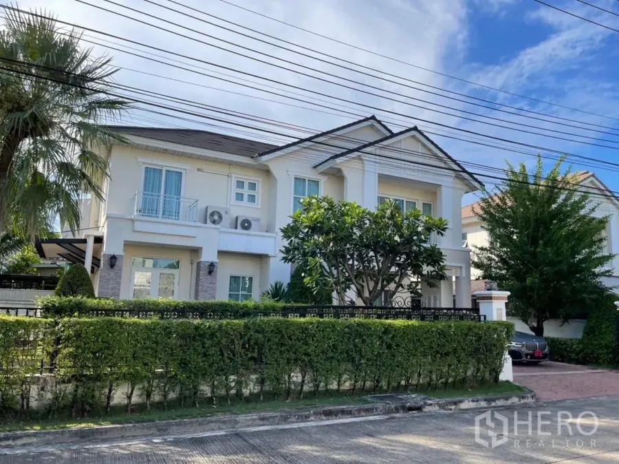 Detached House for rent in Prawet, Bangkok - Front exterior of a two-storey detached house in Prawet, Bangkok with hedge fence and driveway.