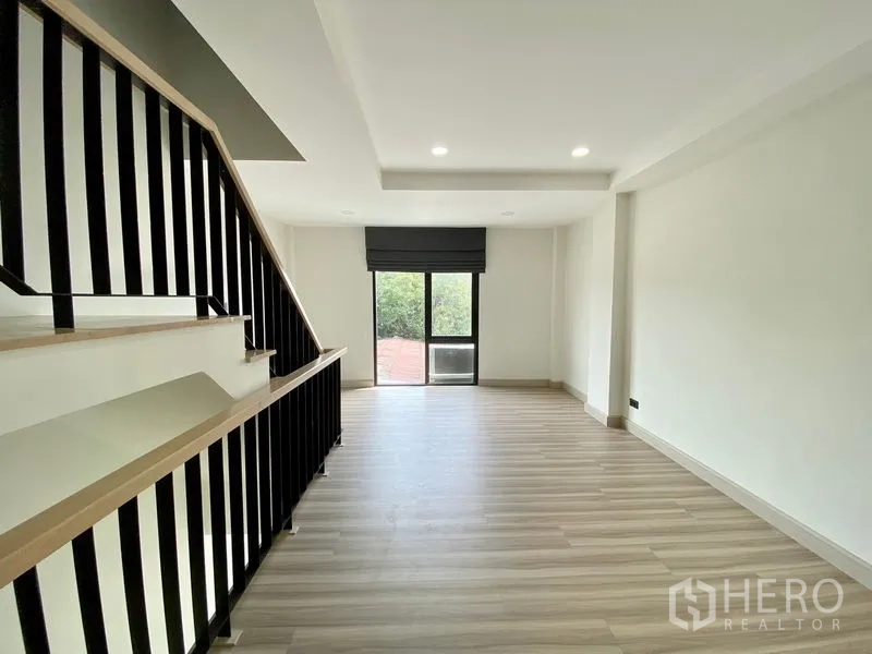 Home Office for rent or sale in Bang Na, Bangkok - Second-floor living space with wood-style floors, recessed lighting and a sliding balcony door.