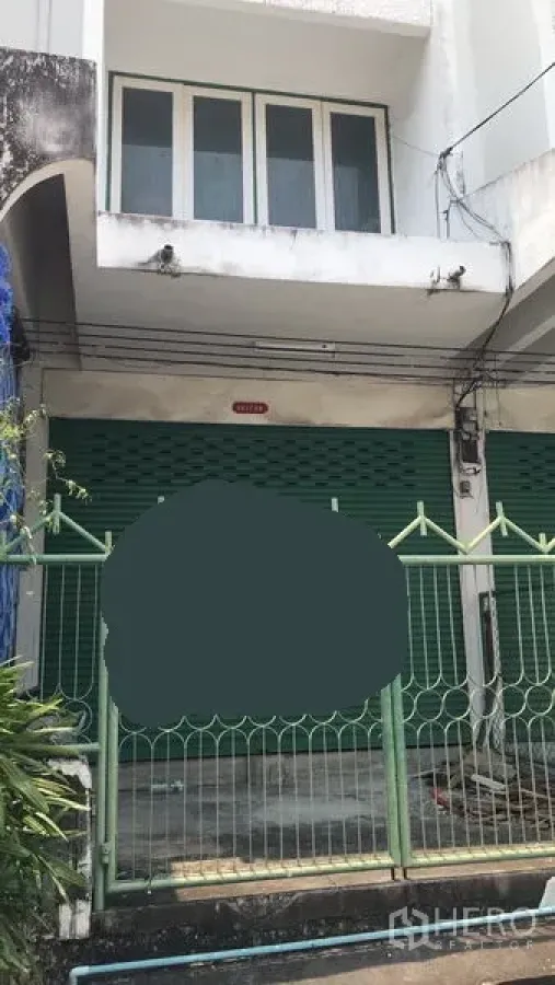 สำนักงานที่บ้าน ให้เช่าในWatthana, Bangkok - ด้านหน้าอาคารโฮมออฟฟิศสไตล์ตึกแถว ประตูม้วนสีเขียว พร้อมรั้วหน้าบ้านและหน้าต่างชั้นบน ในเขตวัฒนา กรุงเทพฯ