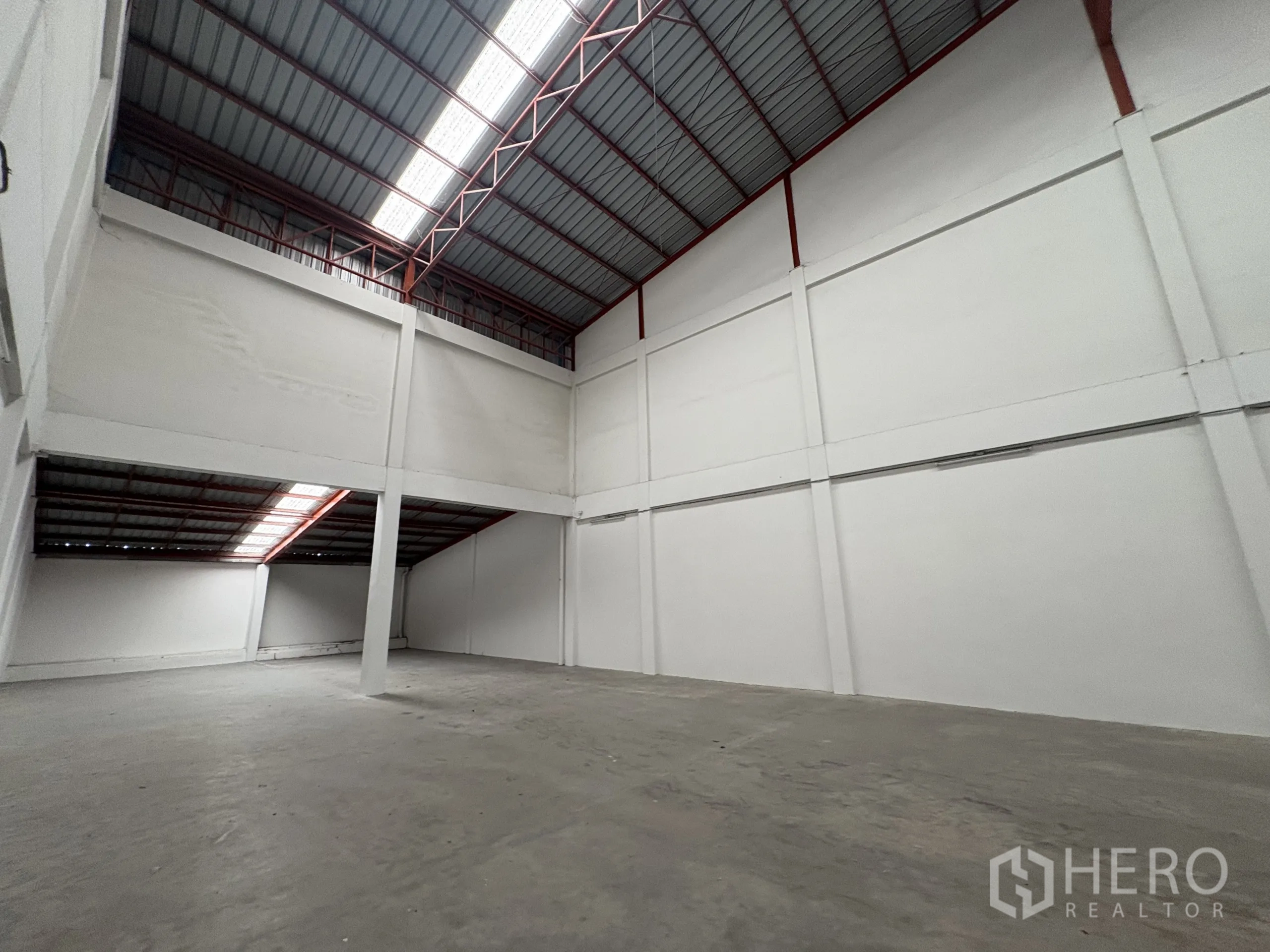 Factory for rent in Phra Samut Chedi, Samut Prakan - Open factory space with partial mezzanine and central column under ventilated roof.