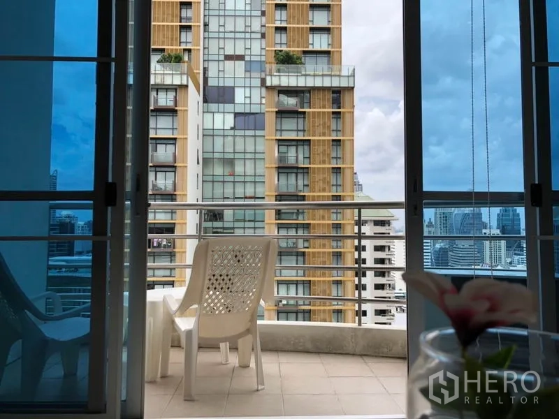 Condominium for rent in Pathum Wan, Bangkok - Balcony with chairs facing a nearby high-rise and city skyline.
