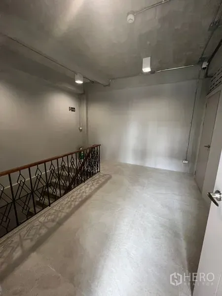 Retail Space for rent in Watthana, Bangkok - Upper landing with industrial metal railing, concrete-look flooring and ceiling lights.