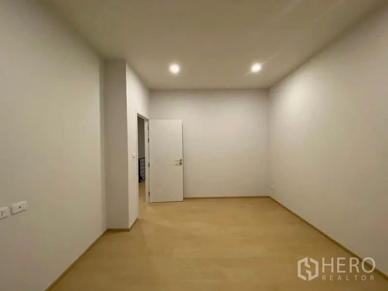 Townhouse for rent in Prawet, Bangkok - Empty room with soft lighting and an open door leading to the hallway.