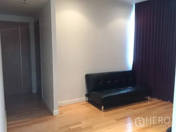 Condominium for sale in Khlong Toei, Bangkok - Quiet study corner with black leather sofa, recessed lighting and purple blackout curtains.