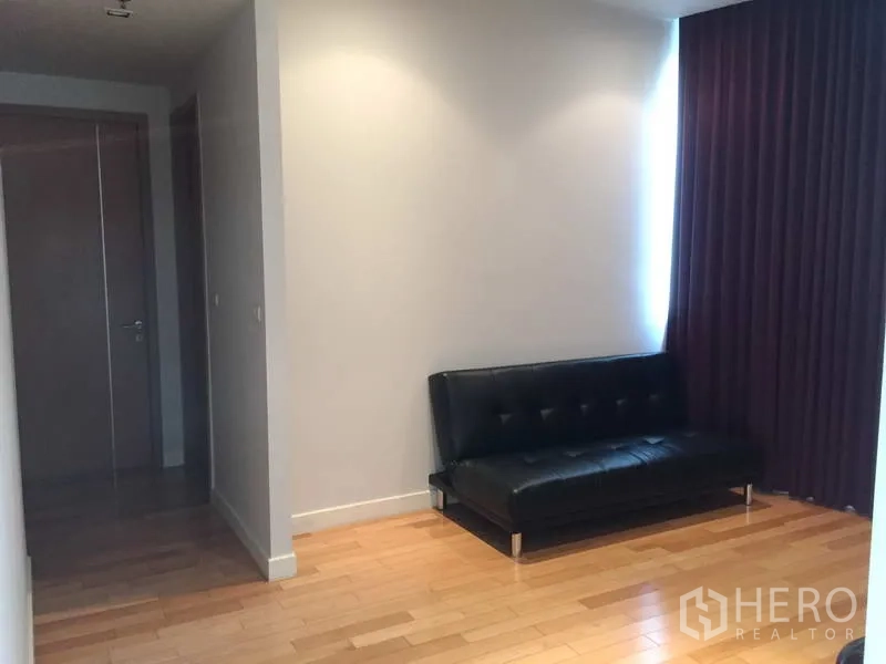 Condominium for sale in Khlong Toei, Bangkok - Quiet study corner with black leather sofa, recessed lighting and purple blackout curtains.