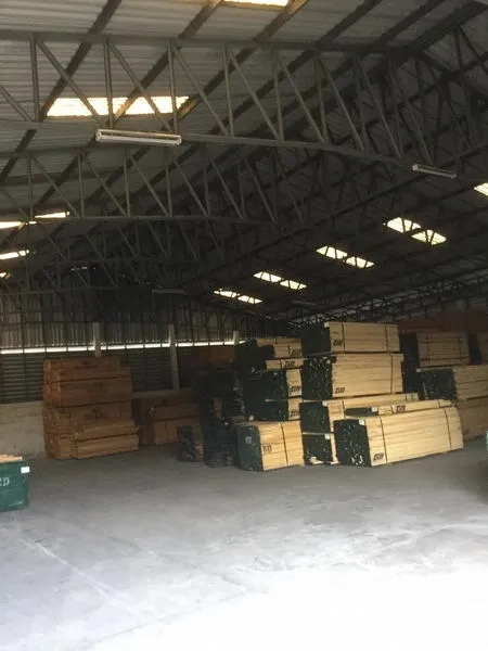 Warehouse for sale in Sai Noi, Nonthaburi - Open storage hall with steel trusses, translucent roof panels, and clear floor space with stacked goods.