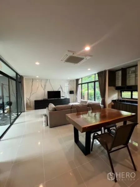 Detached House for rent in Bang Kapi, Bangkok - Open-plan lounge and dining with marble feature wall, TV console, wooden dining table and sliding glass doors.