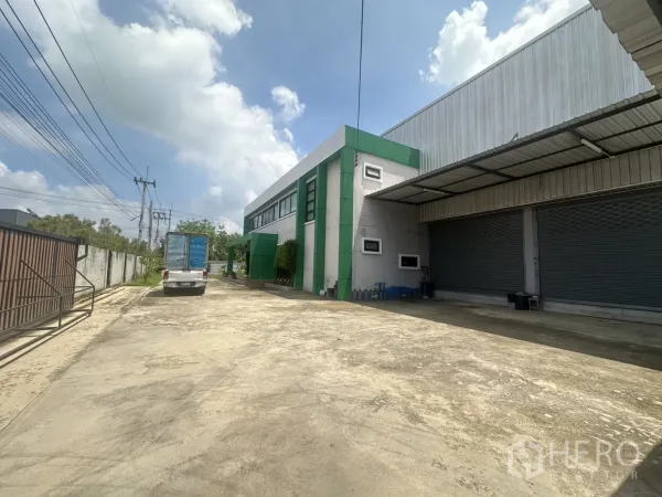 Warehouse for sale in Bang Len, Nakhon Pathom - Long driveway to the warehouse with security gate, power lines and truck access.